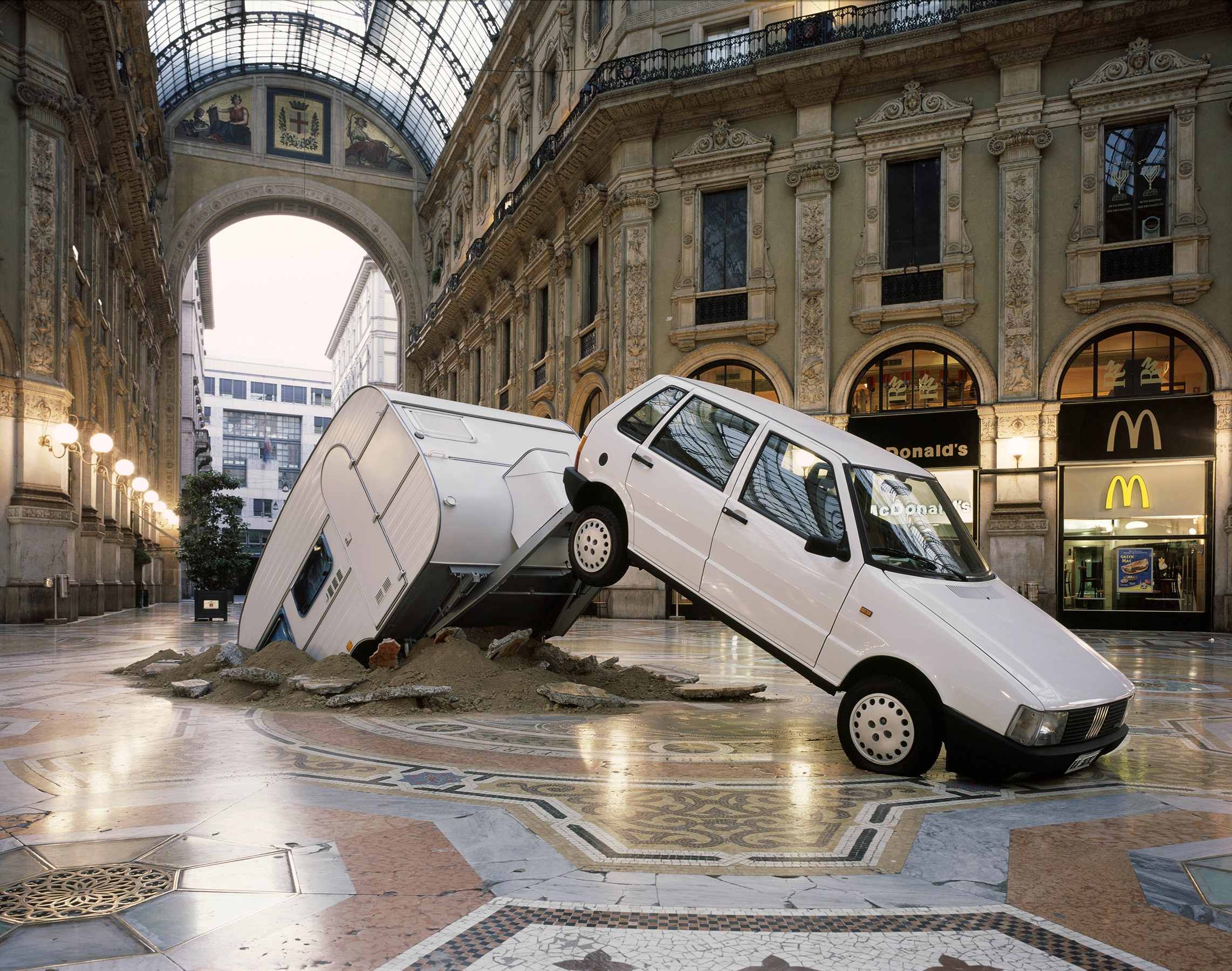 Elmgreen & Dragset artwork where a Fiat Punto caravan has crashed an italian public square in Milan.